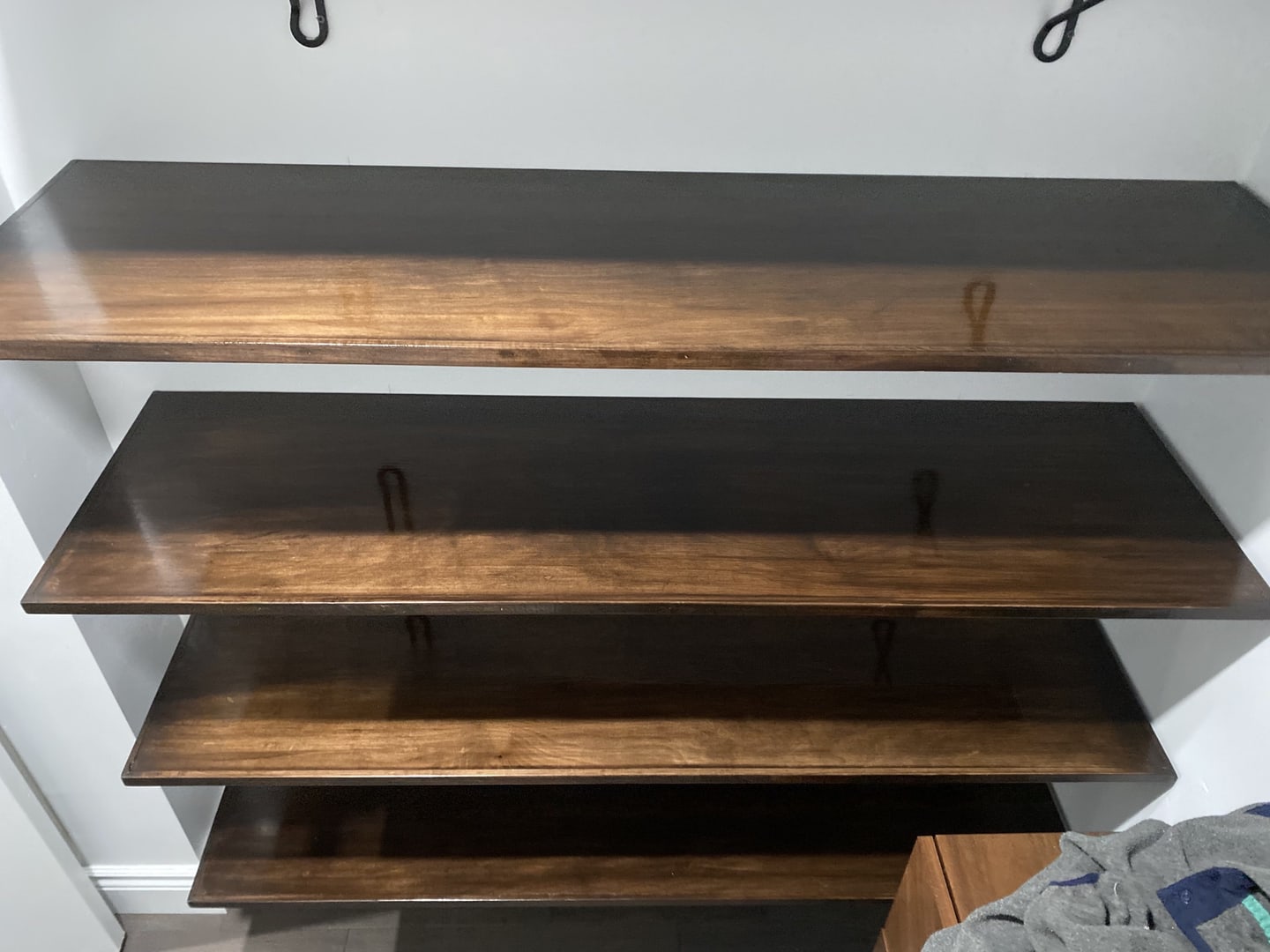 Dark stained wood shelves fitted into a white closet alcove
