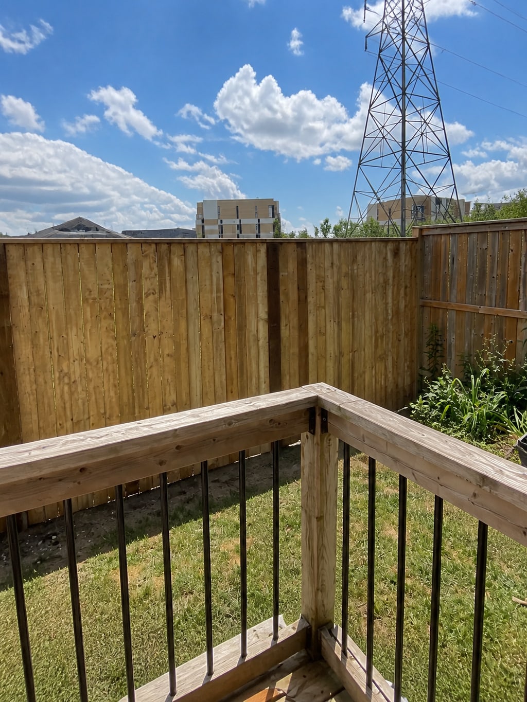 Tall wooden privacy fence viewed from an existing deck railing