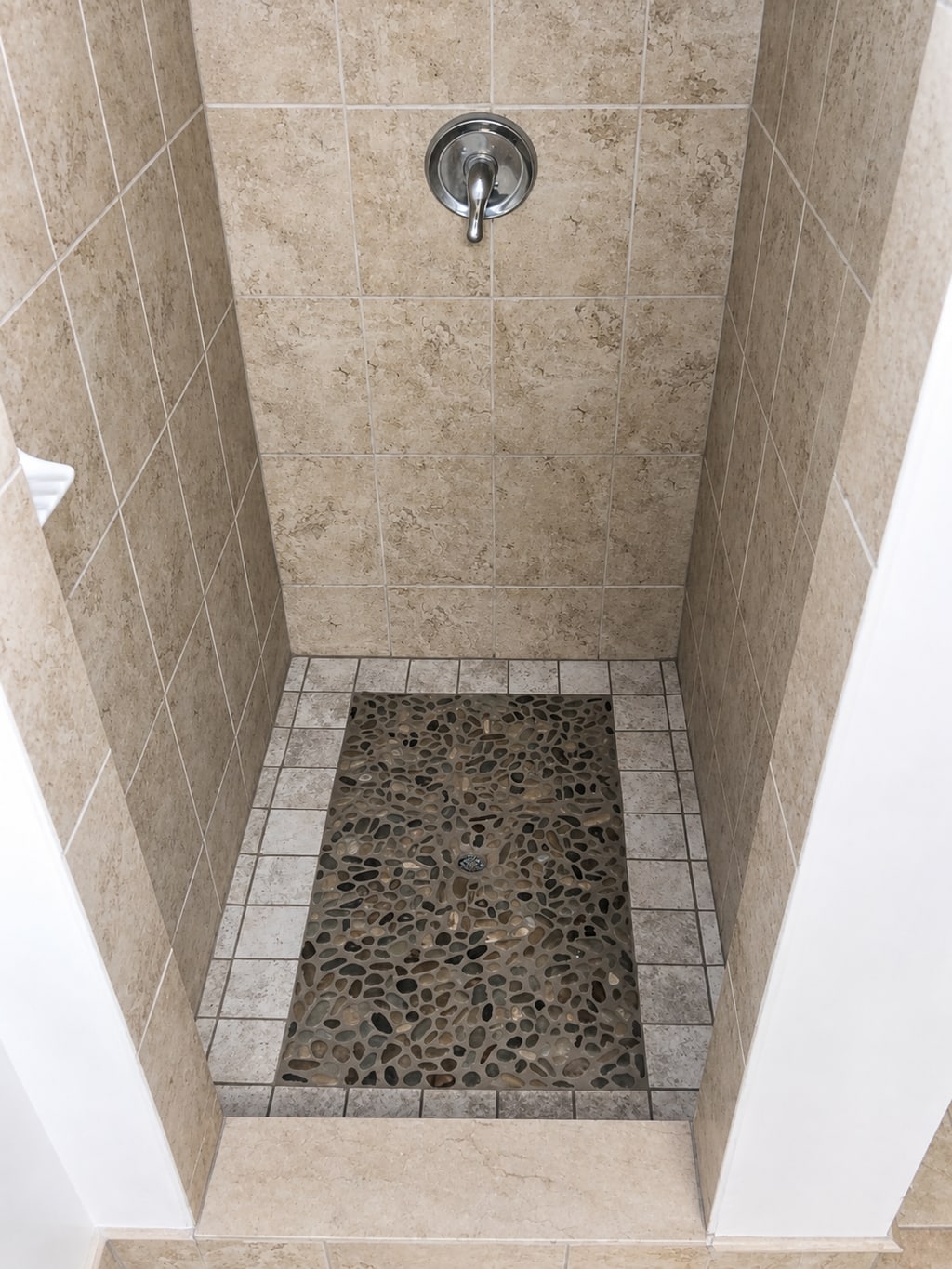 Completed pebble-mosaic shower pan with a tiled perimeter